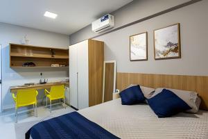 a bedroom with a bed and a desk with yellow chairs at Flats Cotia in Cotia