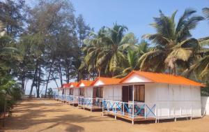 uma fila de casas numa praia com palmeiras em Nikhils Luxury Beach Cottages em Magdāl