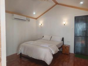 une chambre avec un lit blanc et une fenêtre dans l'établissement Nikhils Luxury Beach Cottages, à Magdāl