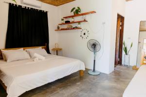 a bedroom with a white bed and a fan at Ozen Freediving Hostel in General Luna