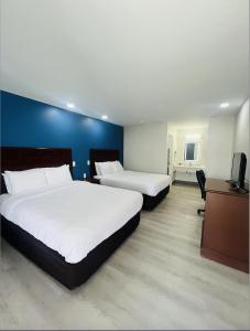 Una habitación de hotel con dos camas y un televisor. en The Hallmark Inn & Suites Newly Renovated Rooms San Antonio Northeast, en San Antonio 3 fotos más