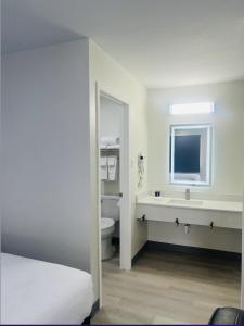 Un baño blanco con lavabo e inodoro. en The Hallmark Inn & Suites Newly Renovated Rooms San Antonio Northeast, en San Antonio