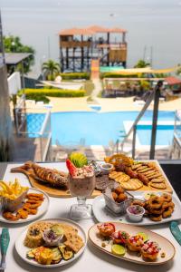 a table topped with plates of food next to a pool at Equinoccio Hotel in Santa Ana