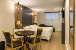 a hotel room with a bed and a table and chairs at Eleganz Suítes Exclusive Centro in Gramado +49 photos