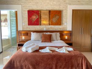 a bedroom with a bed with two towels on it at Chalés Mirante Monte Verde in Monte Verde