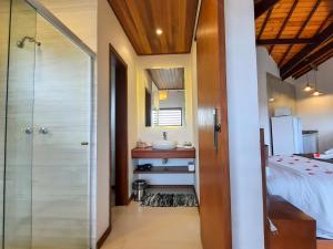 a bathroom with a shower and a sink next to a bed at Chalés Mirante Monte Verde in Monte Verde +29 photos