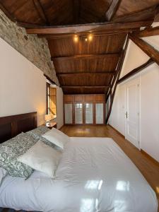 een slaapkamer met een groot wit bed en houten plafonds bij Casa Chita in Tapia de Casariego