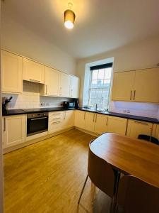 グラスゴーにあるMaster Bedroom in City Centerの白いキャビネットと木製のテーブルのあるキッチン