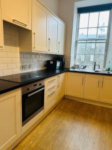 グラスゴーにあるMaster Bedroom in City Centerの白いキャビネットと黒いカウンタートップを備えたキッチン