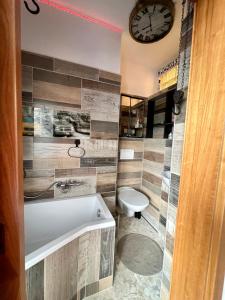 a bathroom with a tub and a toilet and a clock at König Apartmen in Kynšperk nad Ohří