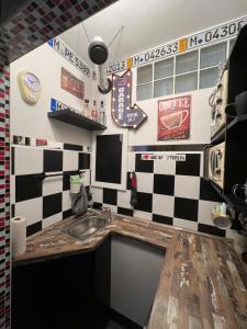 a kitchen with a sink and a checkered wall at König Apartmen in Kynšperk nad Ohří +3 photos
