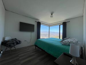 a bedroom with a green bed and a flat screen tv at Casa con vista al Valle del Huasco in Freirina