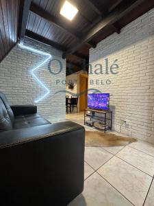 a living room with a couch and a wall with a tv at Chale Bombinhas Porto Belo in Porto Belo