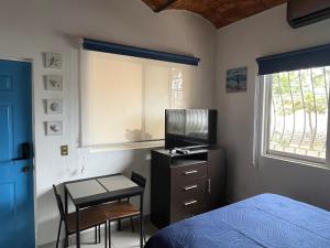 a bedroom with a bed and a table and a television at Le Petit Oasis a few steps from the Beach in Peñita de Jaltemba