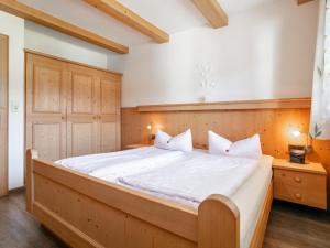 a bedroom with a large wooden bed with white sheets at Landhaus Marchfeld Top 2 in Wildschönau