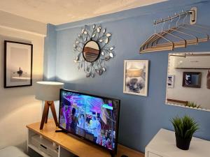 a living room with a flat screen tv on a blue wall at Le Petit Bonheur - Peaceful Rooftop - 3 min Beach in Puerto Vallarta