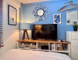 a bedroom with a tv and a blue wall at Le Petit Bonheur - Peaceful Rooftop - 3 min Beach in Puerto Vallarta +19 photos