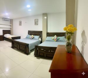 a bedroom with two beds and a vase of flowers on a table at Olas del Mar by GHO Hoteles in Santa Marta +19 photos