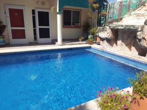 a swimming pool with blue water in front of a house at Le Petit Oasis a few steps from the Beach in Peñita de Jaltemba