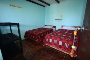 a room with two beds and a tv in it at La Casa EcoExplor in San Pedro de Atacama
