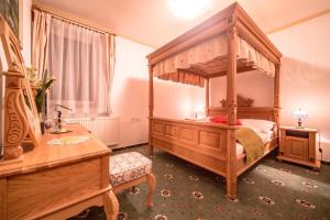 a bedroom with a wooden canopy bed and a table at Hotel Diana in Stráža