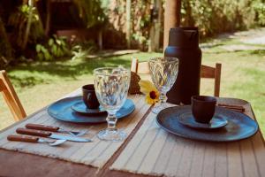 Una mesa de madera con platos y copas de vino encima. en Vila Três - A apenas 2 minutos da praia!, en Caraíva 212 fotos más