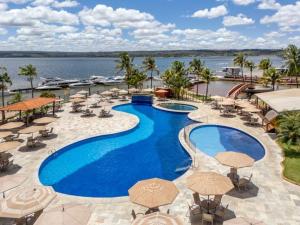 una piscina con ombrelloni, sedie e un bacino d'acqua di Flat Lakeside Beira lago a Brasilia