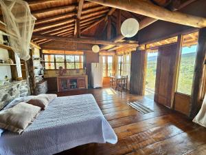 a bedroom with a large bed in a room with wooden floors at Chalés Vila Carrancas - Unidade Serra in Carrancas