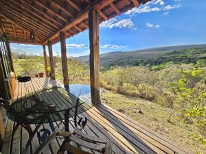 a porch of a cabin with a table and chairs at Chalés Vila Carrancas - Unidade Serra in Carrancas