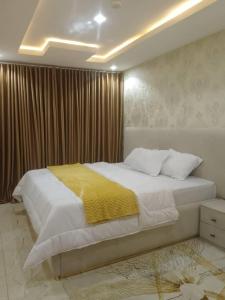 a bedroom with a large bed with a yellow blanket at Aquarian Spring Homes in Ikeja