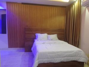 a bedroom with a large bed with a wooden headboard at Aquarian Spring Homes in Ikeja