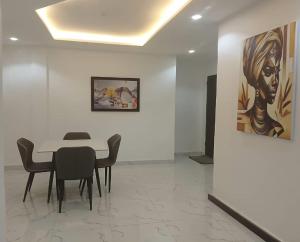 a dining room with a table and chairs and a painting at Aquarian Spring Homes in Ikeja