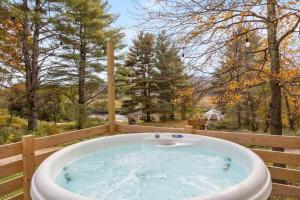 a jacuzzi tub on a fence in a yard at Designer A-Frame Treehouse with hot tub on river in Johnson