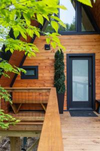 a wooden house with a black door and a bench at Designer A-Frame Treehouse with hot tub on river in Johnson