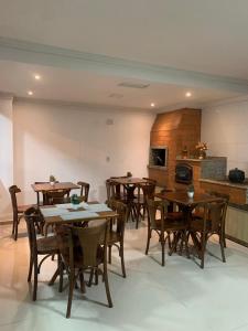 a dining room with wooden tables and wooden chairs at Pousada Vô Nilo in Penha