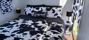 1 cama con edredón y almohadas en blanco y negro en Taranaki Creekside KIWI by Tiny Away, en Stratford