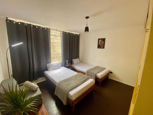 a small room with two beds and a window at Music Guest House in Mexico City