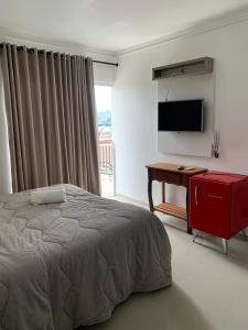 a bedroom with a bed and a desk and a television at Pousada Vô Nilo in Penha +33 photos