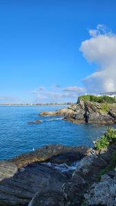 a view of a body of water with rocks at 100 metros da praia do forte in Cabo Frio +6 photos