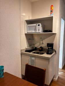a small kitchen with a sink and a microwave at 100 metros da praia do forte in Cabo Frio