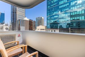 a balcony with two chairs and a view of a city at Quest on Queen Serviced Apartments in Auckland +4 photos