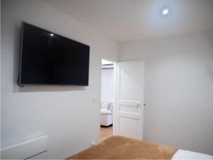 un salon avec une télévision à écran plat sur un mur dans l'établissement Cosy appartement Levallois, à Levallois-Perret