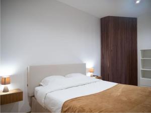 une chambre avec un grand lit blanc et deux lampes dans l'établissement Cosy appartement Levallois, à Levallois-Perret