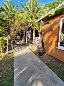 a sidewalk next to a house with palm trees at Cottage 15, Village de la Pointe in Le Vauclin