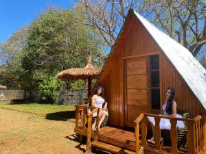 two women sitting on the porch of a small hut at Glamping Guavirá in Ciudad del Este