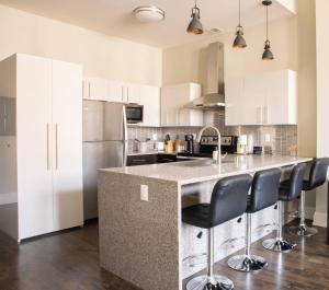 una cucina con armadi bianchi e una grande isola con sgabelli da bar di Downtown Sleek 2BR Loft a Milwaukee