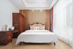 a bedroom with a large white bed and a desk at Weisi Zhenpin Holiday Courtyard in Wushi