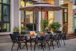 a table with chairs and an umbrella in front of a building at Weisi Zhenpin Holiday Courtyard in Wushi