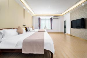 a hotel room with a large bed and a flat screen tv at Weisi Zhenpin Holiday Courtyard in Wushi