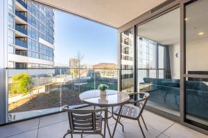 a dining room with a table and chairs and a large window at Stylish Woden Apt Near Hospital w Pool, Parking in Phillip